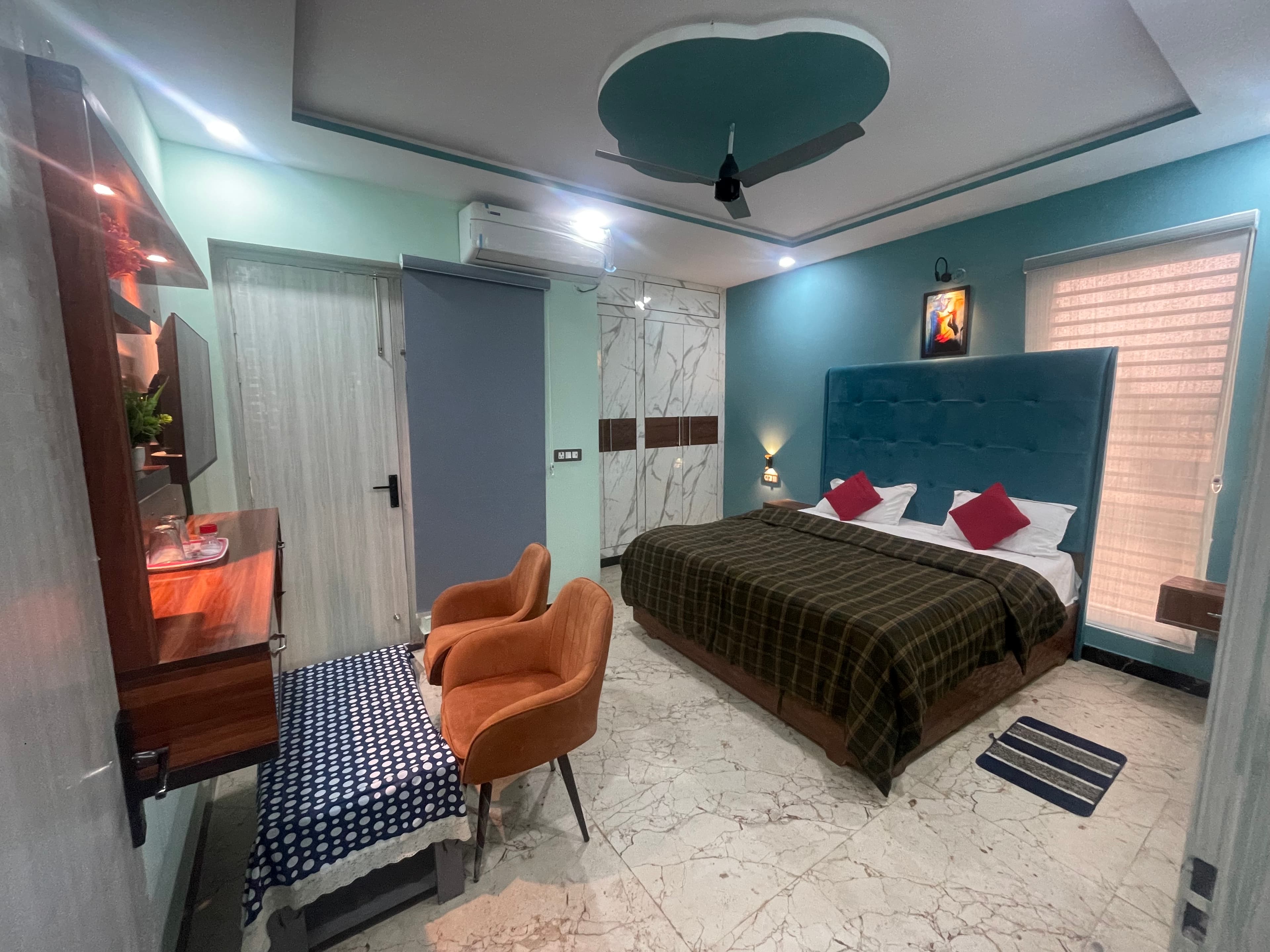 Deluxe AC Room at VMP Villa — teal accent wall with king bed and seating area