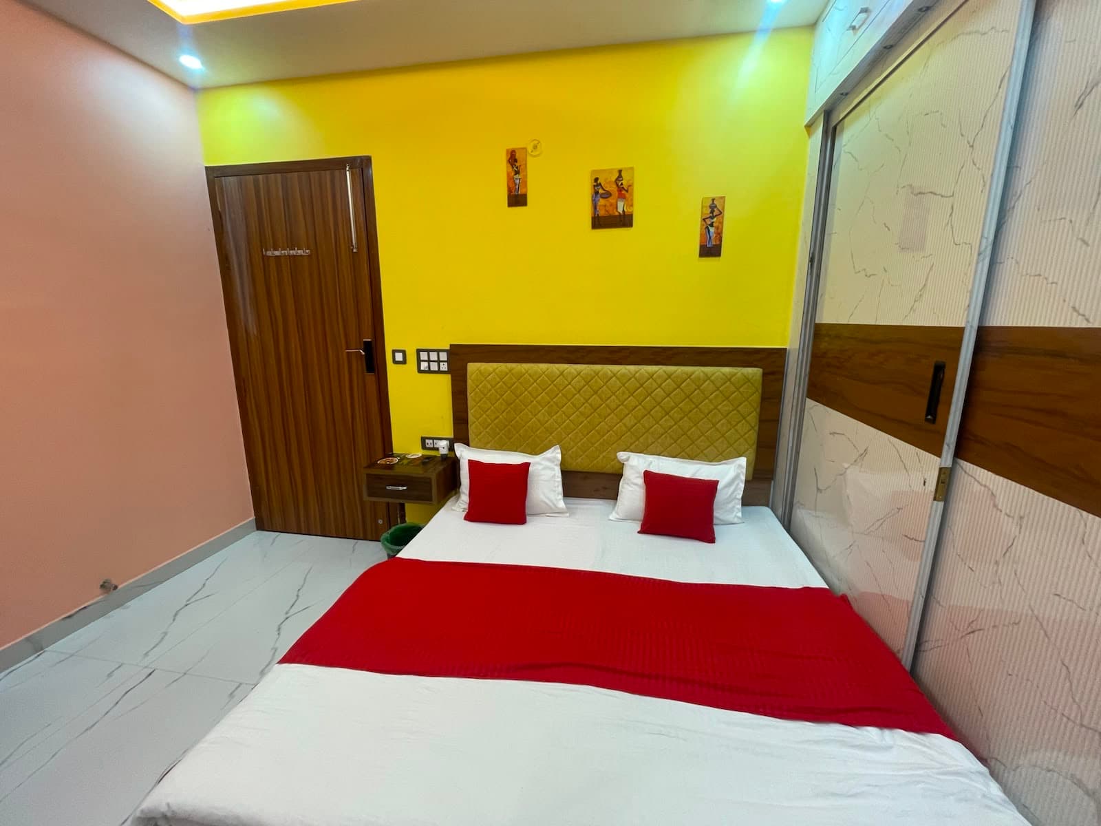 Standard AC Room at VMP Villa — king bed with yellow accent wall and red pillows